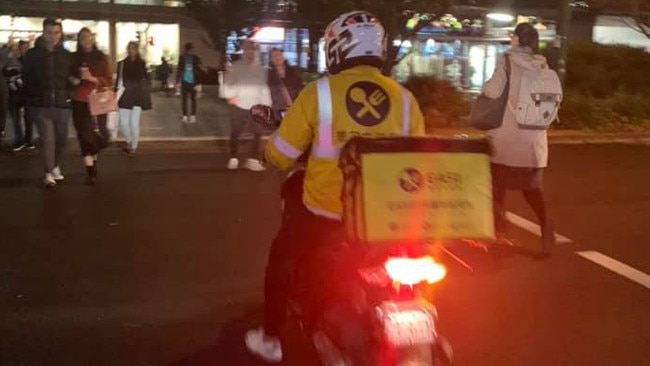 A fast-food delivery driver uses a pedestrian crossing in Box Hill’s centre.