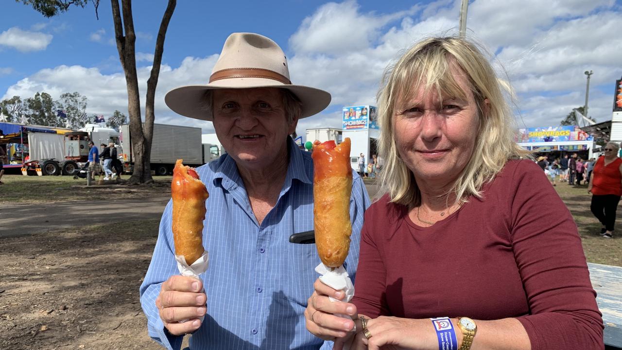 Jim McPhee and Kim Rhodes from Maryborough enjoy a dagwood dog at the Fraser Coast Ag Show for 2021. Photo: Stuart Fast