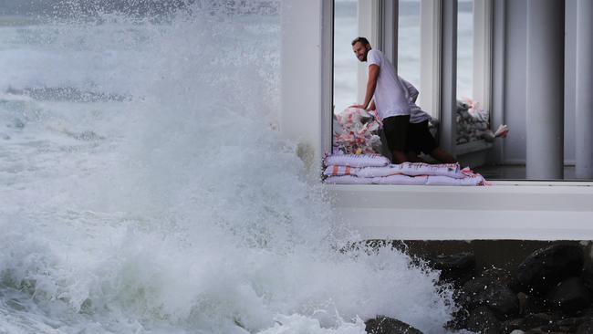 Cyclone Oma is agony for some and ecstasy for others. Staff at Rick Shores at Burleigh Pavilion fight a desperate battle against the king tide and big surf by sandbagging the windows. Picture Glenn Hampson