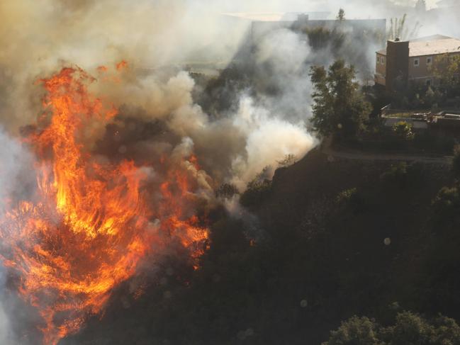 Flames close in on homes threatened by the wind-driven Palisades Fire in Pacific Palisades, California, January 7, 2025. A fast-moving brushfire in a Los Angeles suburb burned buildings and sparked evacuations Tuesday as "life threatening" winds whipped the region. More than 200 acres (80 hectares) was burning in Pacific Palisades, a upscale spot with multi-million dollar homes in the Santa Monica Mountains, shuttering a key highway and blanketing the area with thick smoke. (Photo by David Swanson / AFP)