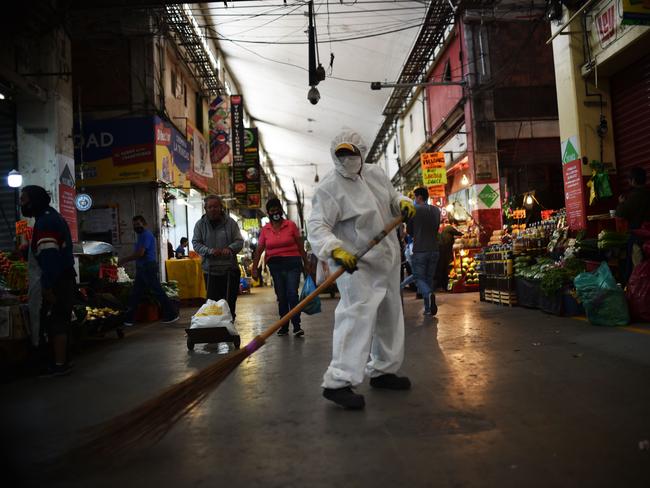 A worker wearing protective gear sweeps the floor at a market in Mexico City. Picture: AFP