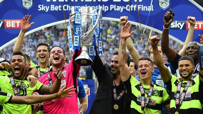 Huddersfield Town's Welsh goalkeeper Danny Ward (centre left) and Huddersfield Town's German head coach David Wagner (centre right) hold up the Championship Playoff trophy.