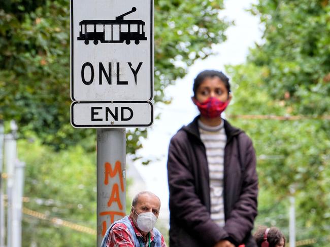 People wait for the tram while wearing a mask in Melbourne on Sunday. Photo: NCA NewsWire / Luis Ascui