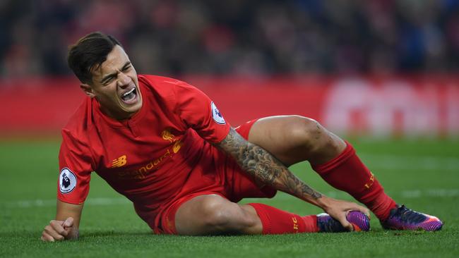 Liverpool's Brazilian midfielder Philippe Coutinho holds his foot as he lies on the pitch injured.