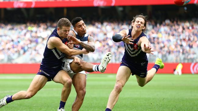 Sam Switkowski bumps Tim Kelly in the act of kicking as Nat Fyfe attempts a smother. Picture: AAP