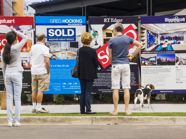 Melbourne, Australia - November 28, 2015: Visitors reading a row of estate agent signs outside a newly-renovated apartment building at 5 Commercial Rd, South Yarra. Formerly a derelict hotel, the site was the focus of Series 11 of popular Channel Nine TV series The Block. a reality renovation contest.