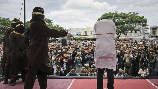 A Shariah law official whips one of two men convicted of gay sex during a public caning outside a mosque in Banda Aceh, Indonesia in 2017.