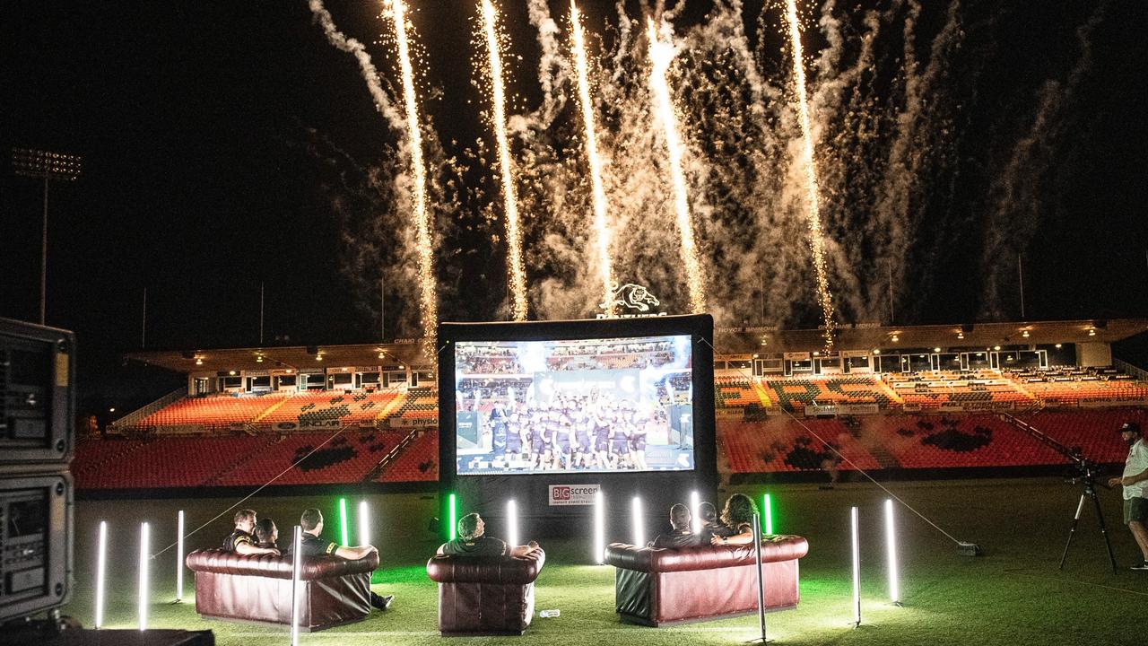 Fireworks go off in the background as Penrith watch their grand final celebrations on the big screen. Picture: Fox League