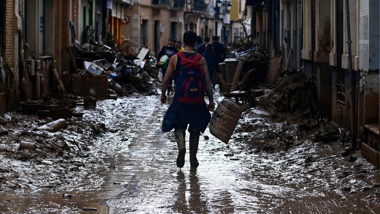 A volunteer walks down a muddy street as he leaves Paiporta on November 3, in the aftermath of devastating floods. Picture: Jose Jordan/AFP