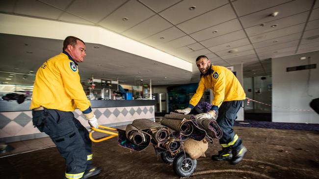 Cobbity Rural Fire Service volunteeers rip up and remove saturated and ruined carpet at Camden Sports Club. Picture: Julian Andrews