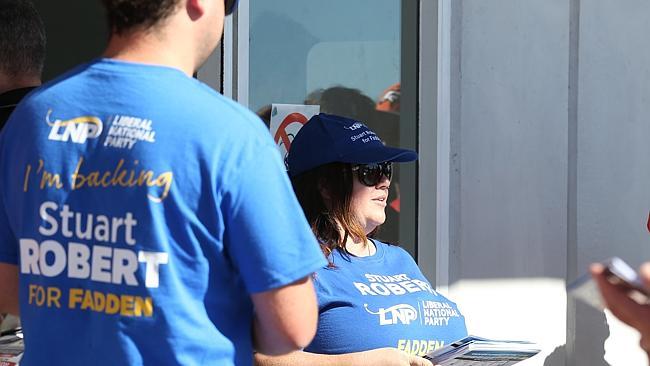 Felicity Stevenson hands out how to vote cards to voters outside the polling station in Oxenford, Gold Coast.