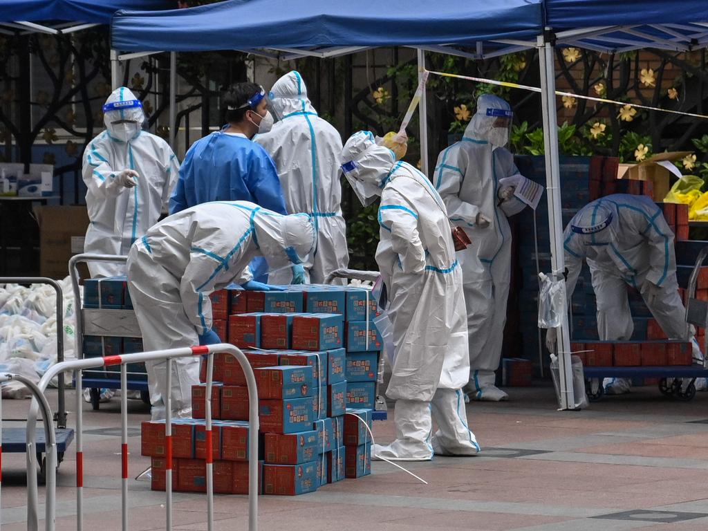 Workers wearing personal protective equipment help distribute food from the local government for residents in a compound during a Covid-19 lockdown in Shanghai on April 10, 2022. Picture: Hector Retamal / AFP