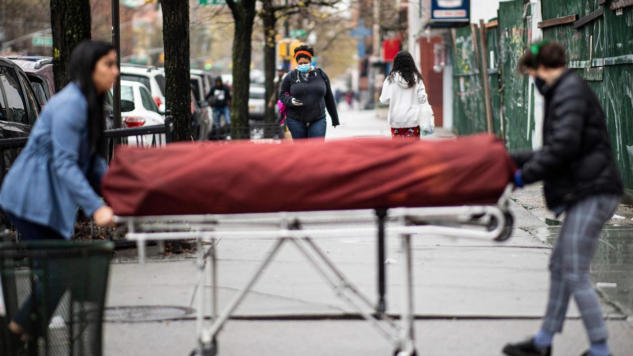 Manager Alisha Narvaez (L) and Lily Sage Weinrieb, Resident Funeral Director at International Funeral &amp; Cremation Services transport a body on a stretcher to the funeral home on April 24, 2020, in the Harlem neighbourhood of New York City. Picture: Johannes Eisele / AFP.