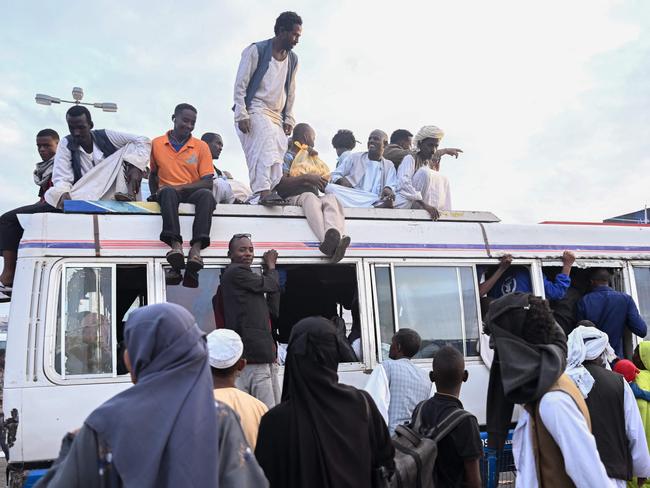 TOPSHOT - People struggling to commute gather around a packed bus in Port Sudan as local transportation is strangled after government authorities reportedly changed two currency notes, invalidating old notes, on December 30, 2024, in the Red Sea port city, where the government loyal to the army is based. Sudan is reeling from 20 months of fighting between the Sudanese army and the paramilitary Rapid Support Forces, led by rival generals, which have led to a dire humanitarian crisis. The war since April 2023 has killed tens of thousands of people and uprooted 12 million, creating what the United Nations has called the world's largest displacement crisis. (Photo by AFP)