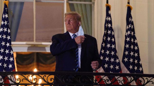 US President Donald Trump takes off his facemask as he arrives at the White House upon his return from Walter Reed Medical Centre.