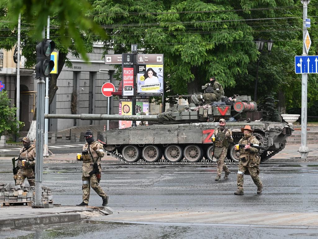 Fighters of Wagner private mercenary group cross a street as they get deployed near the headquarters of the Southern Military District in the city of Rostov-on-Don.