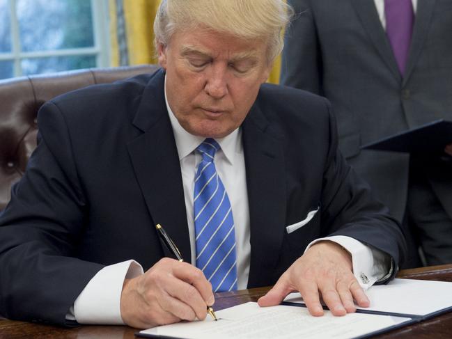 TOPSHOT - US President Donald Trump signs an executive order withdrawing the US from the Trans-Pacific Partnership in the Oval Office of the White House in Washington, DC, January 23, 2017. Trump the decree Monday that effectively ends US participation in a sweeping trans-Pacific free trade agreement negotiated under former president Barack Obama. / AFP PHOTO / SAUL LOEB