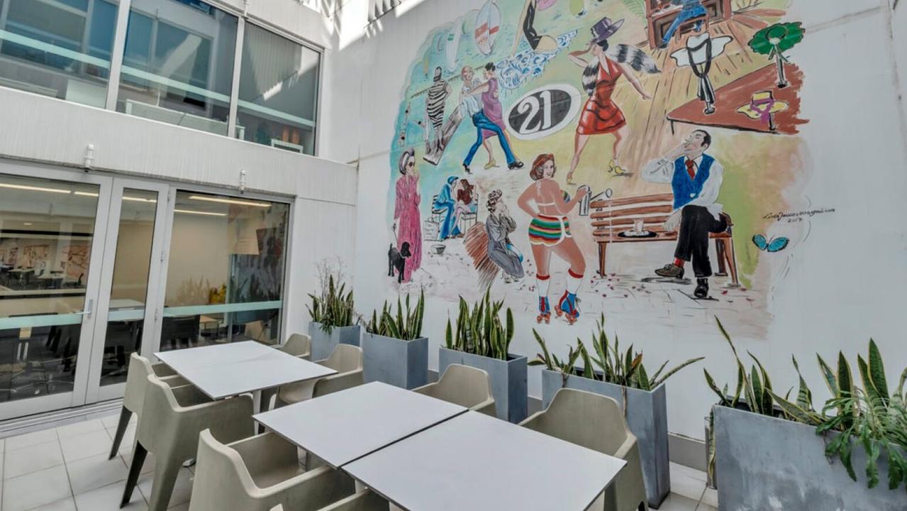 A mural decorates one of the walls of an outdoor lunch areas at the building.