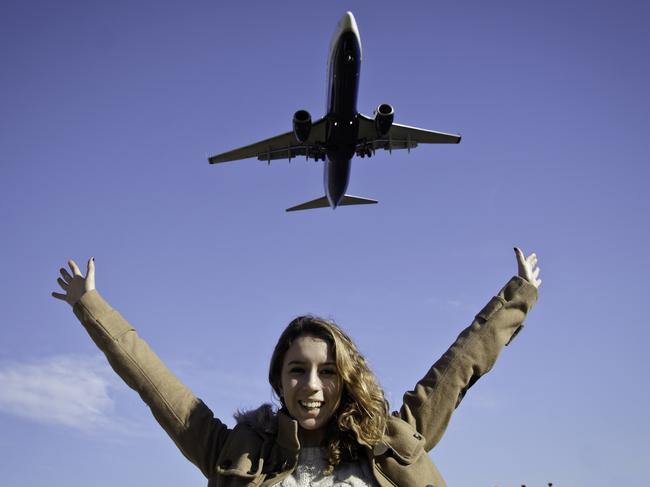 Young woman greeting to a airplane with the lifted armsMore like this