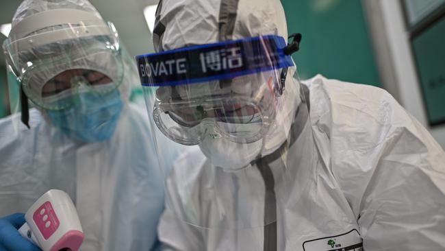 Medical workers check information as they take swab samples from people to be tested for COVID-19 in Wuhan. Picture: AFP