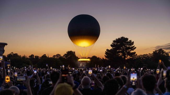 Visitors take pictures of the Olympic cauldron as it rises high after sunset. Picture: Getty Images