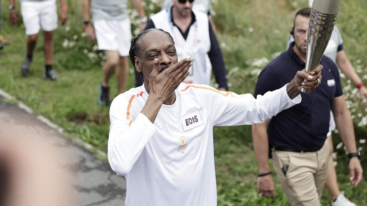 US rapper Snoop Dogg gestures as he holds the torch. Photo by STEPHANE DE SAKUTIN / POOL / AFP.