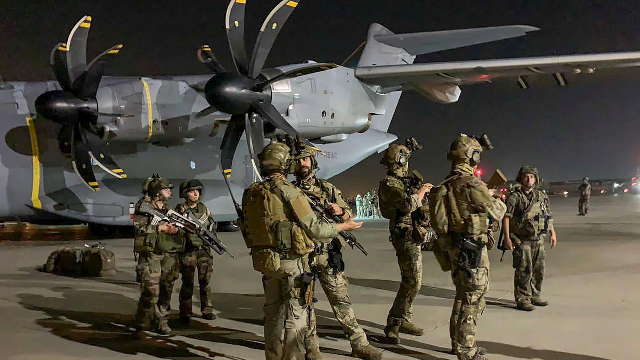 French soldiers stand guard near a military plane at airport in Kabul.