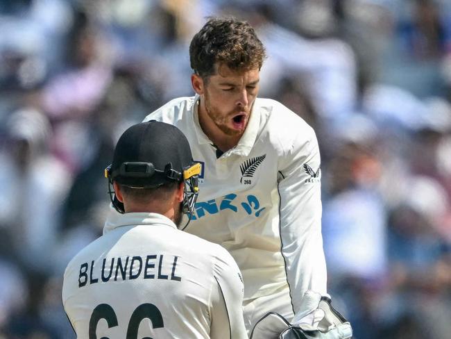 TOPSHOT - New Zealand's Mitchell Santner celebrates with his teammate Tom Blundell (L) after taking the wicket of India's captain Rohit Sharma during the third day of the second Test cricket match between India and New Zealand at the Maharashtra Cricket Association Stadium in Pune on October 26, 2024. (Photo by Punit PARANJPE / AFP) / -- IMAGE RESTRICTED TO EDITORIAL USE - STRICTLY NO COMMERCIAL USE --