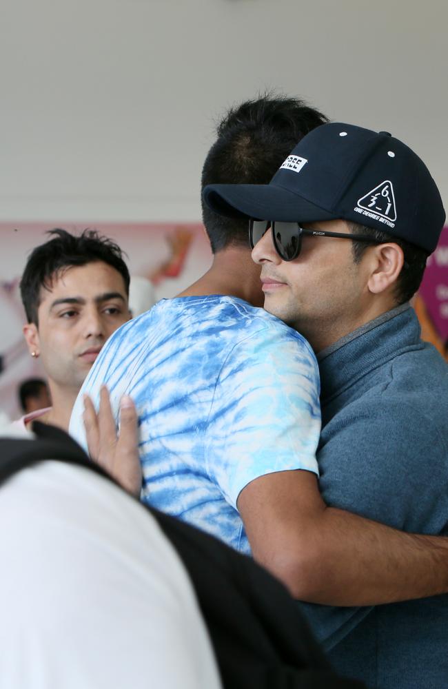 Ghanashyam Ghimire, wearing sunglasses, is comforted by members of the Nepalese community at Adelaide Airport upon arrival on Sunday. Picture: AAP / Emma Brasier