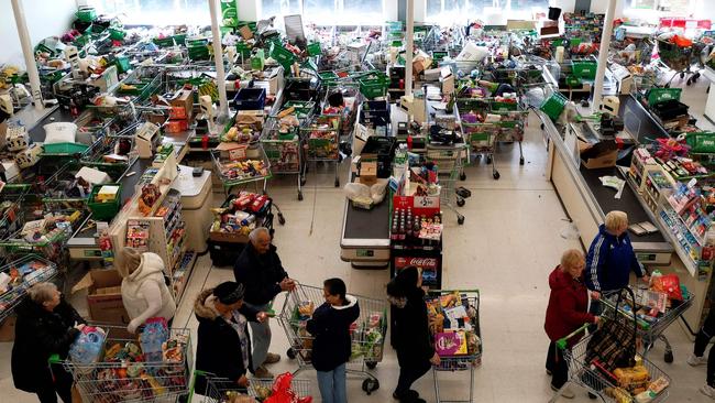 Trolleys piled high for delivery are seen as shoppers queue at the checkout of a supermarket in London. Picture: AFP