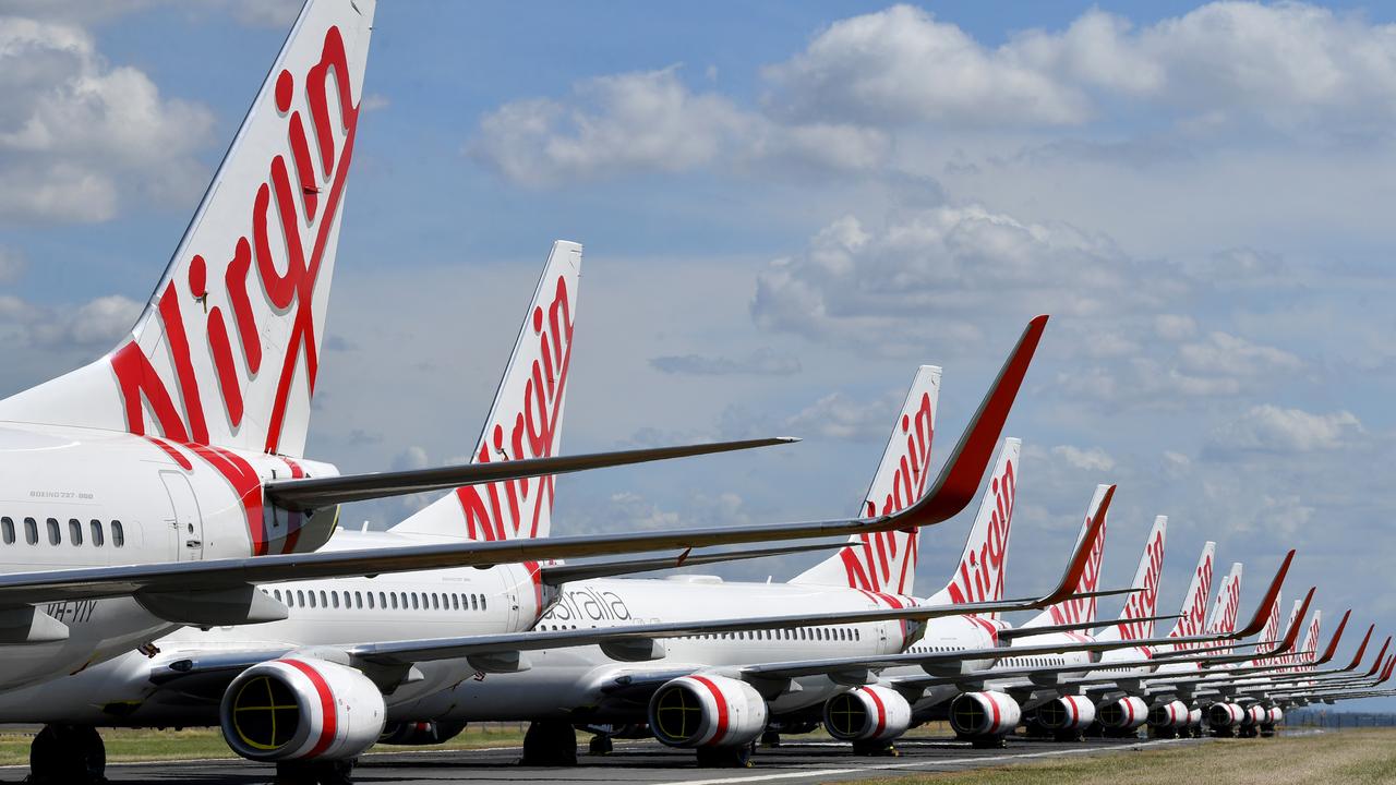 Grounded Virgin Australia aircraft are seen parked at Brisbane Airport in Brisbane, Tuesday, April 7, 2020. Brisbane Airport Corporation (BAC) is working with airlines by accommodating up to 100 grounded aircraft free of charge in response to government-mandated travel restrictions that have grounded a significant proportion of Australia's airline fleet because of the Coronavirus (COVID-19). (AAP Image/Darren England) NO ARCHIVING