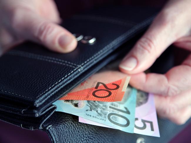Adult woman female hand pulling out Australian money from a leather wallet.