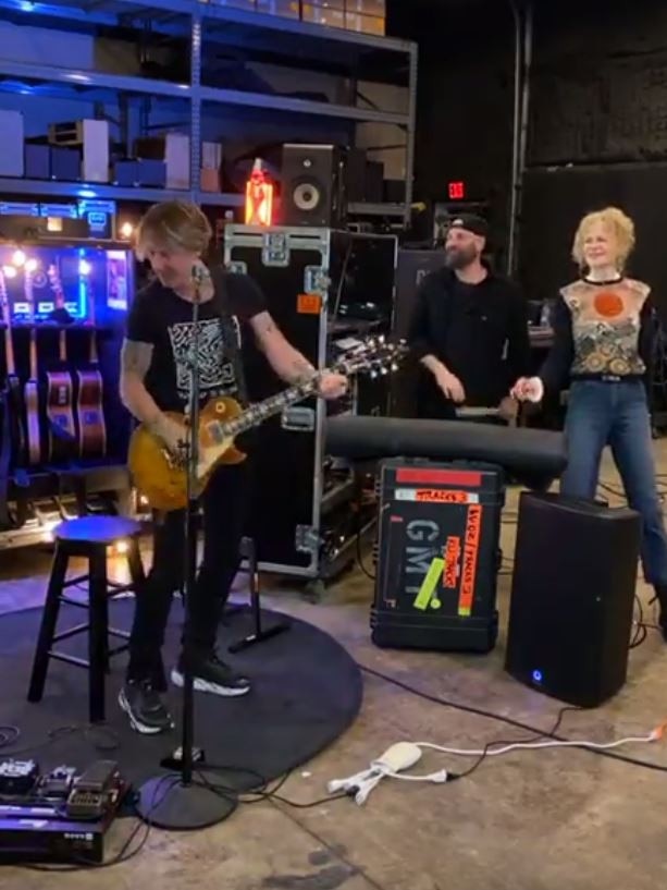 Keith Urban live-streaming from his Nashville warehouse as Nicolas Kidman watches on.