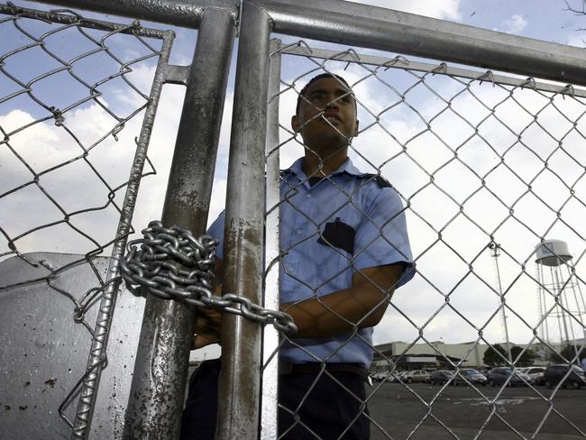 FILE - In this June 19, 2009 file photo, a security guard stands behind a fence at the General Motors assembly plant in Valencia, Venezuela. General Motors says it has halted operations in Venezuela after authorities seized a factory. The plant was confiscated on Wednesday, April 19, 2017, in what GM called an illegal judicial seizure of its assets. GM says its due process rights were violated and it will take legal steps to fight the seizure. (AP Photo/Juan Carlos Hernandez, File)