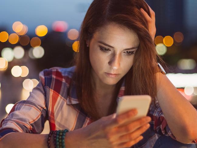 Unhappy woman texting on her smartphone at the bridge.