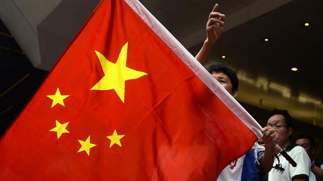 This photo taken on October 2, 2014 shows a pro-China supporter holding a Chinese national flag shouts near the site of pro-democracy demonstrators in Hong Kong. A deadline for pro-democracy demonstrators to clear Hong Kong's barricaded streets loomed October 5, after overnight clashes with riot police, as the city's Beijing-backed leader claimed the disorder now risked "serious consequences" for public safety.  AFP PHOTO / DALE DE LA REY