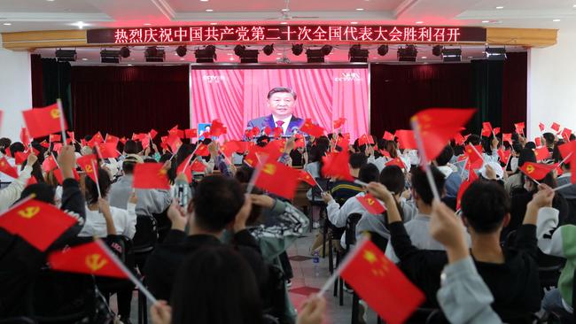 Chinese wave national and Communist Party flags as they watch the opening session of the 20th Chinese Communist Party Congress in Huaibei, in China’s eastern Anhui province. Picture: AFP