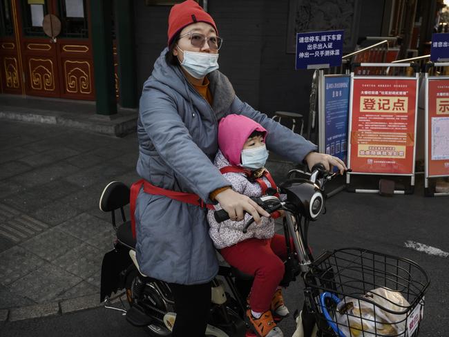 A woman and her daughter wear protective masks as they ride on a scooter through Beijing. Picture: Getty