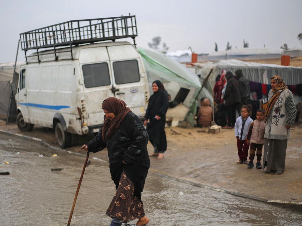 Displaced Palestinians wade in puddles amid rainy weather at a makeshift tent camp in Rafah in the southern Gaza Strip on February 2. Picture: Mohammed Abed / AFP