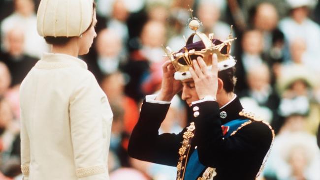 Prince Charles, watched by Queen Elizabeth II, places the gold coronet of The Prince of Wales on his head at his investiture in 1969. Picture: Getty Images