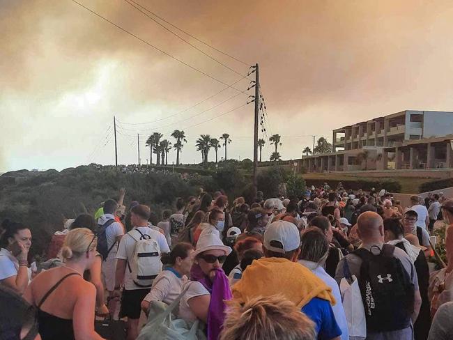 TOPSHOT - Tourists are evacuated from hotels during a wildfire on the Greek island of Rhodes on July 22, 2023. Three coastguard boats were leading more than 20 vessels in an emergency evacuation effort to rescue people from the Greek island, where fire has been raging out of control for five days. (Photo by STRINGER / Eurokinissi / AFP)