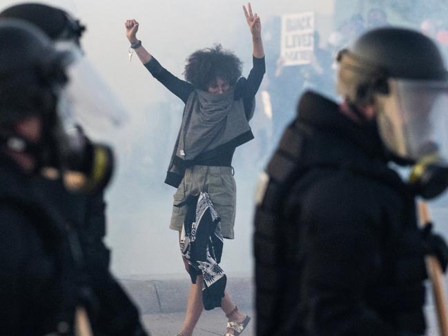 A woman flashes the peace sign while walking backwards in a cloud of tear gas during a protest at 72nd and Dodge Streets, Omaha, Nebraska. Picture: Chris Machian/Omaha World-Herald via AP