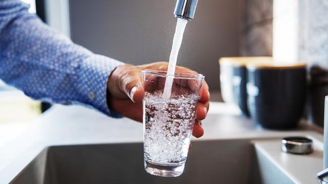 Mature male hand  pouring a glass of water from tap in the kitchen sink