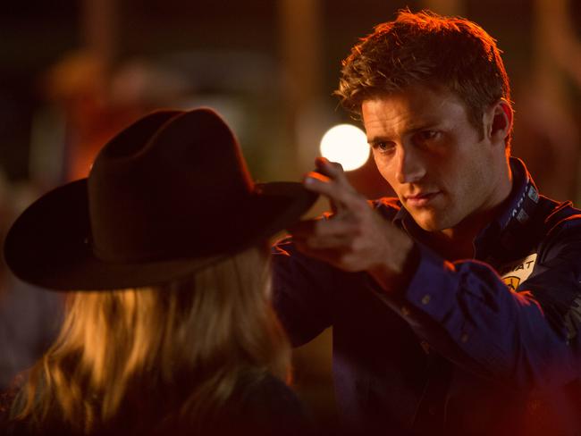 Britt Robertson (in cowboy hat, back to camera) and Scott Eastwood in a scene from film The Longest Ride