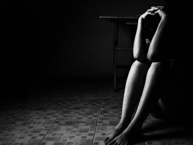 a woman sitting on ground with arm around lower head, sexual violence , sexual abuse, human trafficking concept with shadow edge in white tone, rape. Picture: iSTOCK