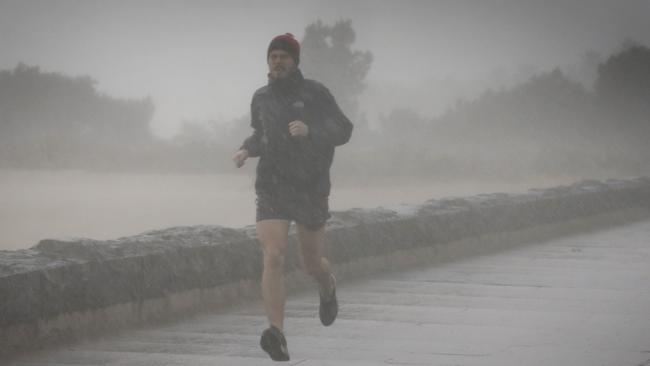 A brave jogger got caught out in the wind and rain on Tuesday. Picture: David Caird