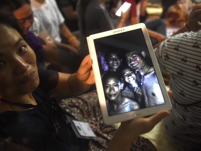 A family member shows a picture of four of the twelve missing boys. Picture: AFP