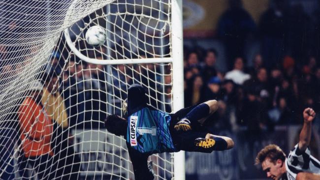 Former West Adelaide keeper Peter Blazincic makes a spectacular flying attempt to stop Adelaide City's goal from scorer Brad Hassell in 1995.