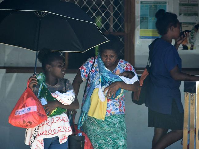 A family leaves a hospital building in downtown of Honiara, as people rushed from their offices and fled to higher ground after a strong earthquake. Picture: AFP.