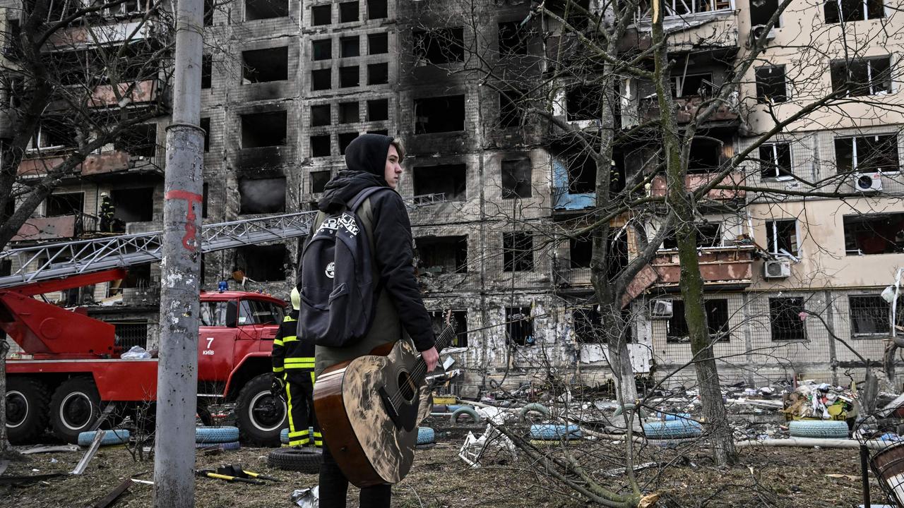 Teenager Maksim Korobych holds his guitar as he stands in front of a destroyed apartment building in the northwestern Obolon district of Kyiv. Picture: Aris Messinis / AFP